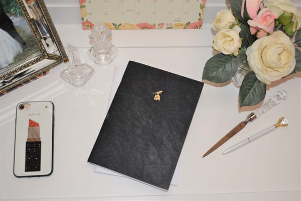 Bieffe Italian Journal Set: Black journal and white journal with small gold imprints of a bird perched upon stack of books